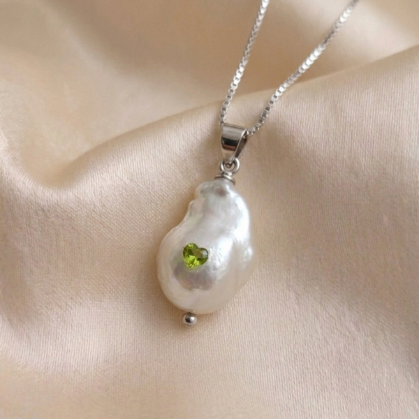 A handcrafted organic baroque pearl pendant set with a heart-shaped peridot cubic zirconia.